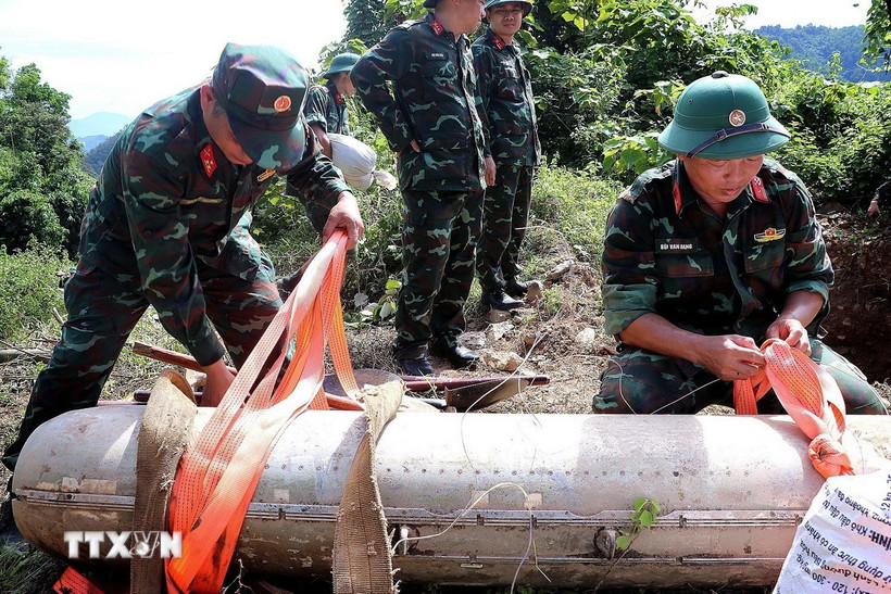 Cán bộ, chiến sỹ chuyên ngành cẩn trọng thực hiện kiểm tra bom CBU-87 trước khi đưa xuống hố hủy nổ. (Ảnh: Thanh Hải/TTXVN)