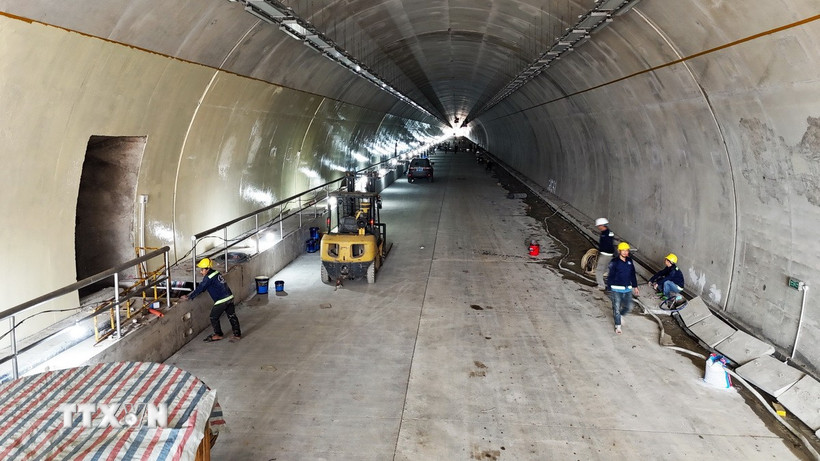 Công nhân và các phương tiện, máy móc thi công các hạng mục bên trong ống hầm. (Ảnh: Hữu Quyết/TTXVN)