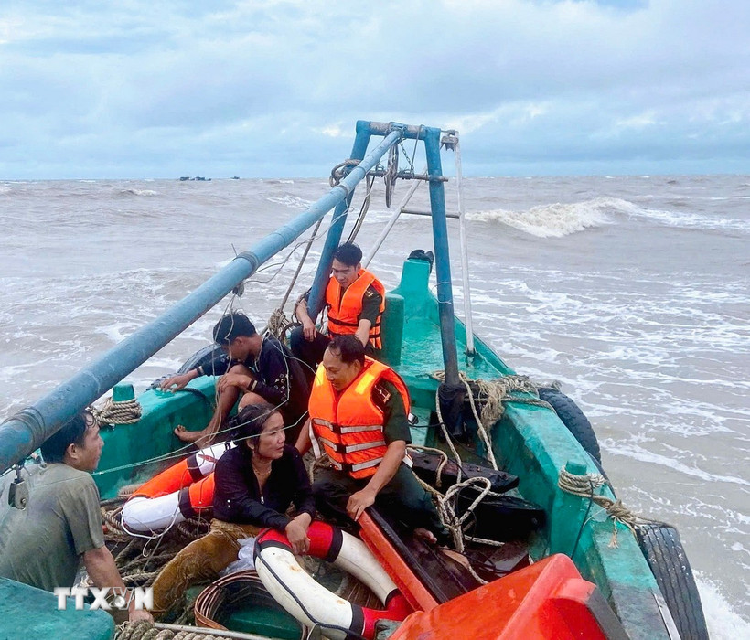 Hai ngư dân gặp nạn được tổ công tác Đồn Biên phòng Khánh Hội cứu đưa lên tàu an toàn. (Ảnh: TTXVN phát)