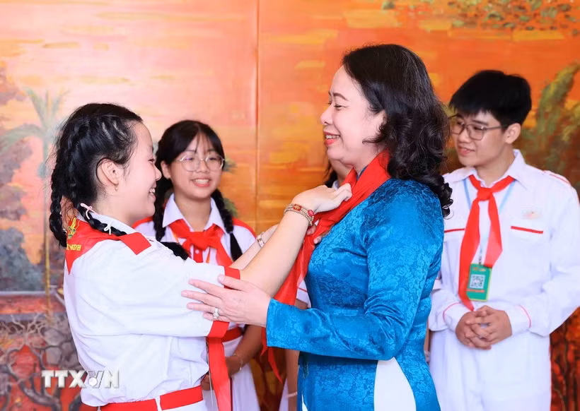 Đại diện thiếu nhi đeo khăn quàng đỏ cho Phó Chủ tịch nước Võ Thị Ánh Xuân. (Ảnh: An Đăng/TTXVN)