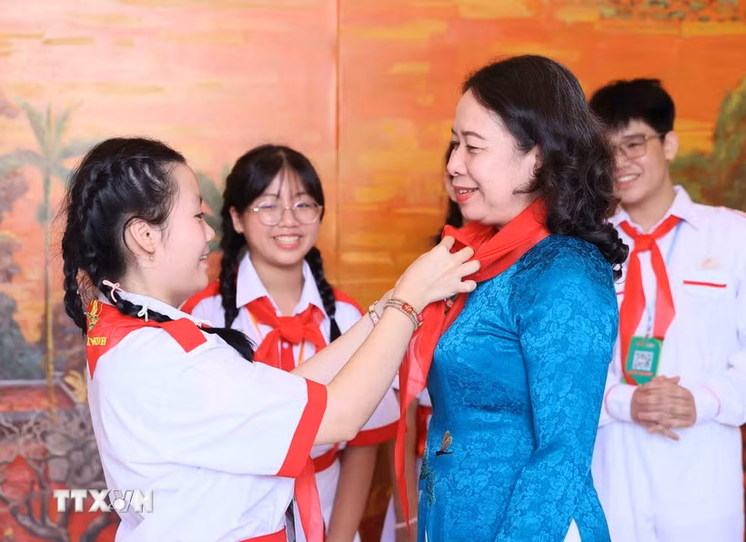 Đại diện thiếu nhi đeo khăn quàng đỏ cho Phó Chủ tịch nước Võ Thị Ánh Xuân. (Ảnh: An Đăng/TTXVN)