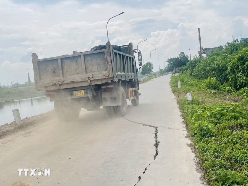 Phương tiện hàng ngày vẫn lưu thông qua những đoạn đê sông Nhuệ (xã Chuyên Mỹ) bị rạn nứt ảnh hưởng lớn đến an toàn đê. (Ảnh: Tuyết Mai/TTXVN)