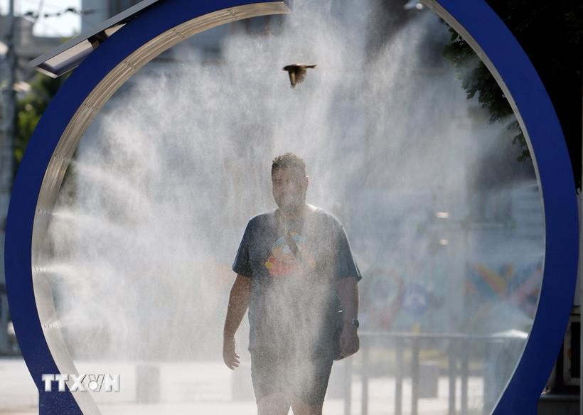 Một người đàn ông làm mát tại thiết bị phun nước ở Bucharest, Romania. (Ảnh: THX/TTXVN)