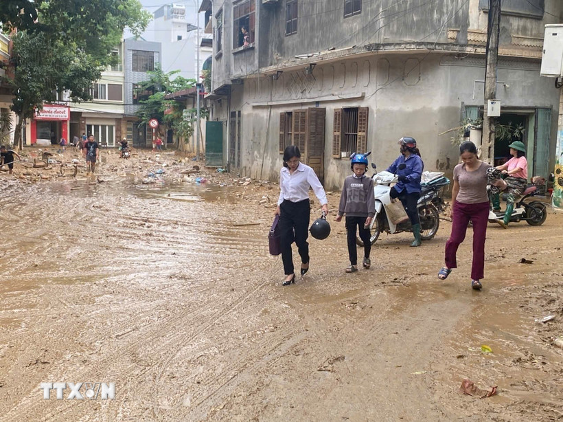 Người dân trở về nhà sau khi sơ tán tránh lũ. (Ảnh: TTXVN)