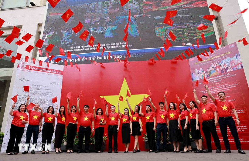 Người dân Thủ đô lưu lại kỷ niệm những khoảnh khắc ý nghĩa cùng lá cờ Tổ quốc và bản tin đặc biệt tại trụ sở TTXVN. (Ảnh: Nhật Anh/TTXVN)