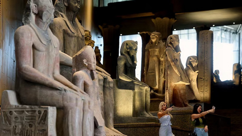 Khách du lịch đứng cạnh các hiện vật trưng bày tại Đại Bảo tàng Ai Cập - nơi sẽ chính thức mở cửa vào tháng 11/2025. (Ảnh: Reuters)