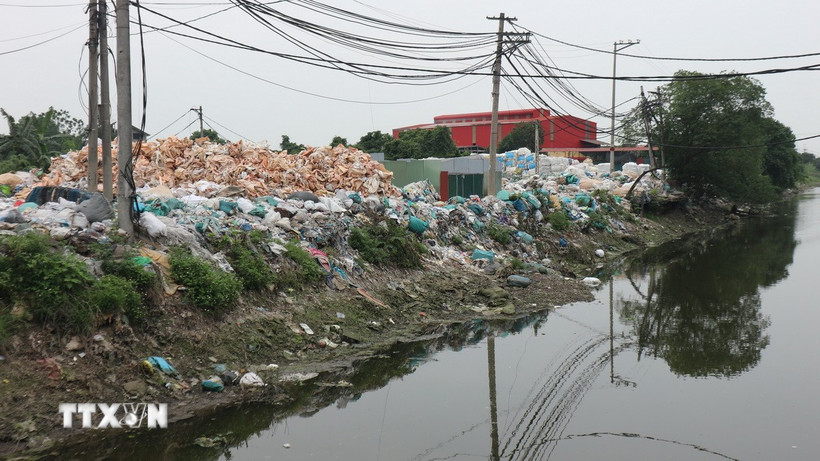 Rác thải nhựa của thôn Minh Khai được tập kết ngay cạnh bờ sông, gây ô nhiễm nghiêm trọng môi trường nguồn nước. (Ảnh: Mạnh Khánh/TTXVN)