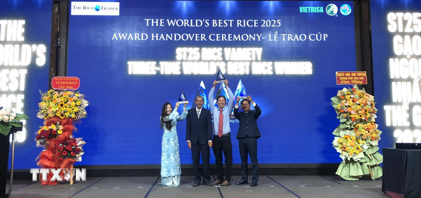 Anh Hùng lao động Hồ Quang Cua cùng các con nâng cao cúp "Gạo ngon nhất thế giới" năm 2025 tại buổi lễ. (Ảnh: Nguyễn Văn Việt/TTXVN)