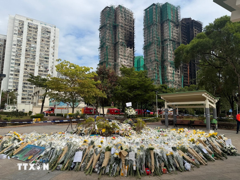 Hàng nghìn bông hoa được người dân mang đến gần hiện trường vụ cháy để bày tỏ niềm thương tiếc với các nạn nhân. (Ảnh: Mạc Luyện/TTXVN)