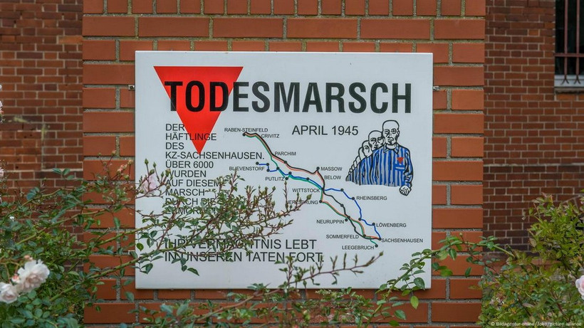 Một tấm bảng trên bức tường gạch đỏ tưởng niệm cuộc diễu hành tử thần Sachsenhausen, hiển thị bản đồ và hình ảnh các tù nhân đang bị đưa đi hành hình. (Ảnh: DW)