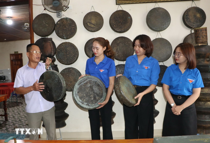 Ông Long giới thiệu những chiếc chiêng do mình sưu tầm với các đoàn viên thanh niên. (Ảnh: Đinh Hương/TTXVN)