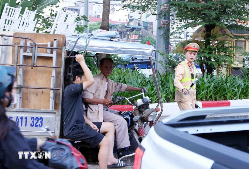 Lực lượng CSGT thuộc Tổ công tác đặc biệt Công an TP Hà Nội dừng xe, kiểm tra và xử lý 1 trường hợp người điều khiển xe ba bánh, bốn bánh tự sản xuất, lắp ráp chở hàng cồng kềnh. (Ảnh: Phạm Kiên/TTXVN)
