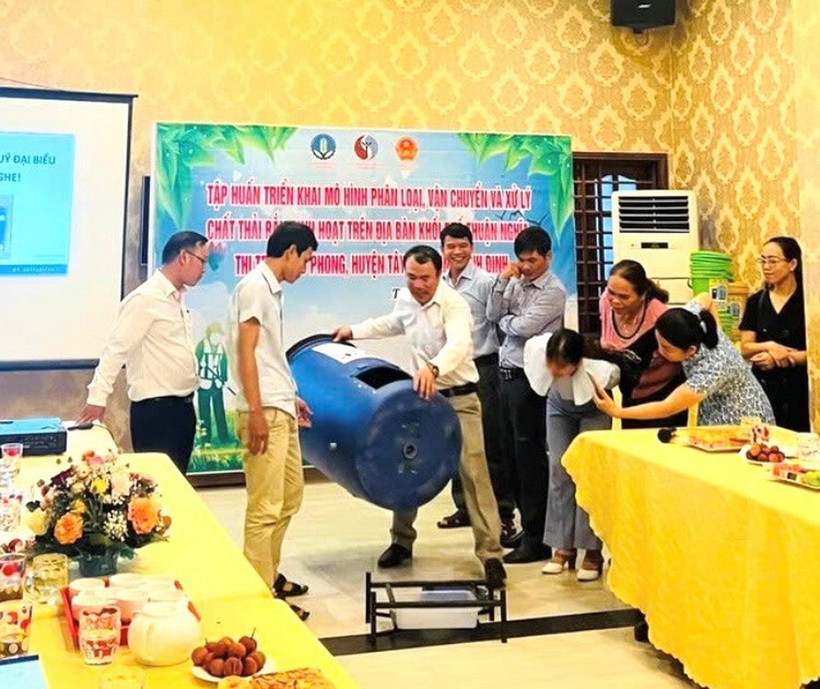 Tiến sỹ Võ Anh Khuê (thứ 3, bên trái sang) hướng dẫn sử dụng thùng ủ rác có thể tích 220 lít cho người dân ở thị trấn Phú Phong, huyện Tây Sơn, tỉnh Bình Định. (Ảnh: Vusta)