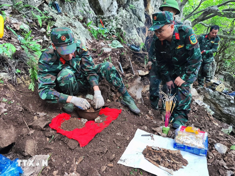 Trung tá Nguyễn Trung Kiên, Phó Chủ nhiệm Chính trị, Bộ Chỉ huy Quân sự tỉnh Hà Giang, trực tiếp chỉ đạo cất bốc 4 bộ hài cốt liệt sỹ vừa được tìm thấy tại khu vực Điểm cao 211. (Ảnh: TTXVN phát)