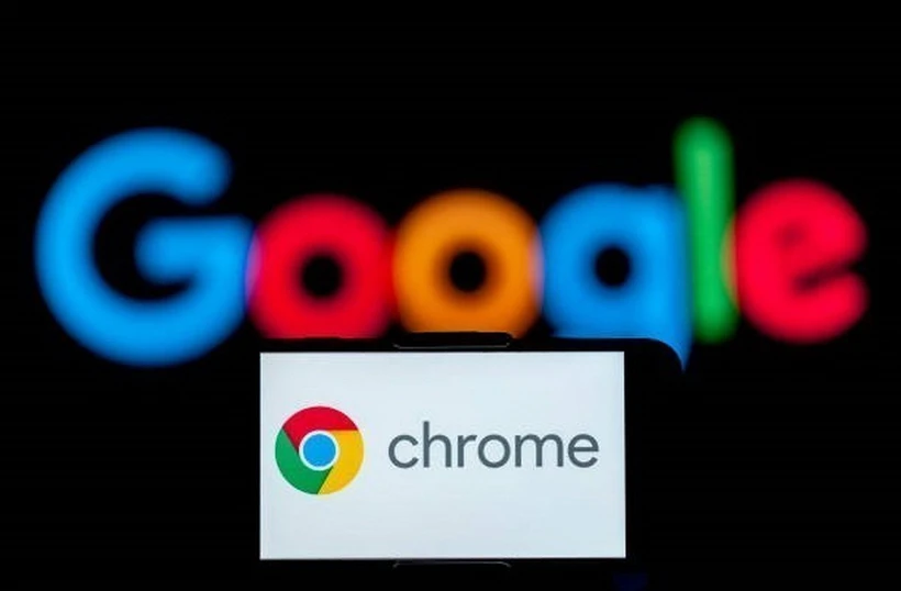 Biểu tượng Chrome trên màn hình điện thoại và biểu tượng Google (phía sau). (Ảnh: Getty Images/TTXVN)