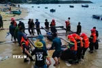 Lực lượng vũ trang tỉnh Đắk Lắk và chính quyền địa phương giúp dân cẩu kéo các tàu, bè nuôi trồng thủy sản lên khu vực an toàn. (Ảnh: TTXVN phát)
