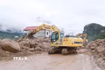 Các phương tiện máy móc tập trung san gạt cây cối, đất đá góp phần thông đường tạm thời cho nhân dân đi lại. (Ảnh: Quý Trung/TTXVN)