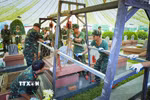 Phần nắp mộ liệt sỹ được nâng lên bằng hệ thống pa lăng xích. Đây là một trong những sáng kiến trong quá trình khai quật lấy mẫu của cán bộ, chiến sỹ Bộ Chỉ huy Quân sự tỉnh Điện Biên. (Ảnh: Xuân Tư/TTXVN)