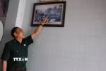 Cựu chiến binh Trần Dân bên bức hình chụp cùng đồng đội tại Dinh Độc Lập vào 13h30 ngày 30/4/1975. (Ảnh: Hoàng Ngà/TTXVN)
