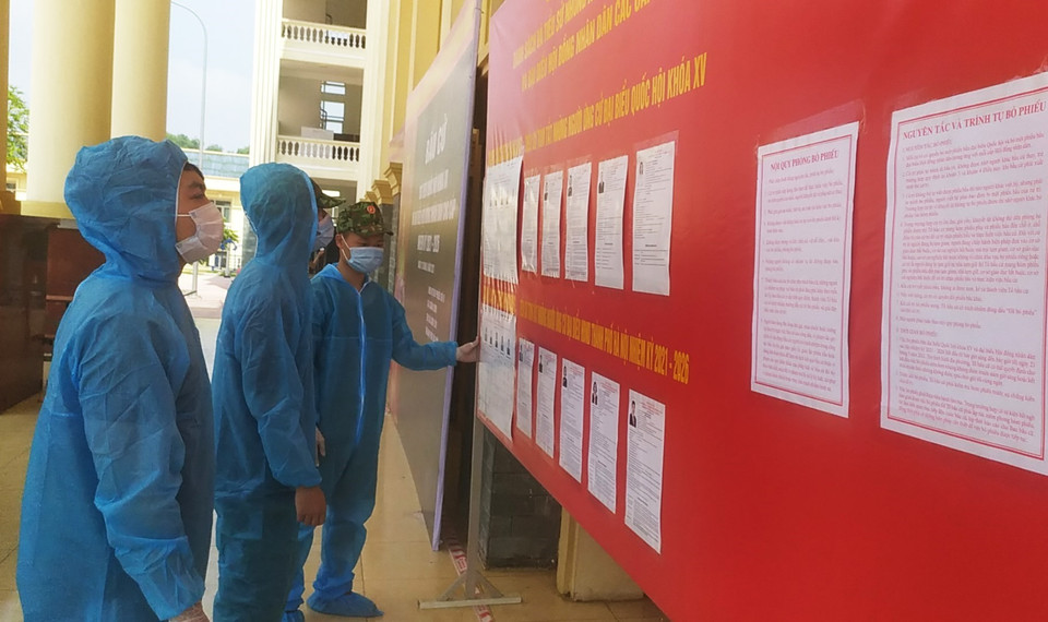 Các chiến sỹ và công dân xem tiểu sử ứng cử viên niêm yết tại khu cách ly phòng, chống dịch COVID-19 Trường Quân sự Bộ Tư lệnh Thủ đô Hà Nội. (Ảnh: TTXVN phát)