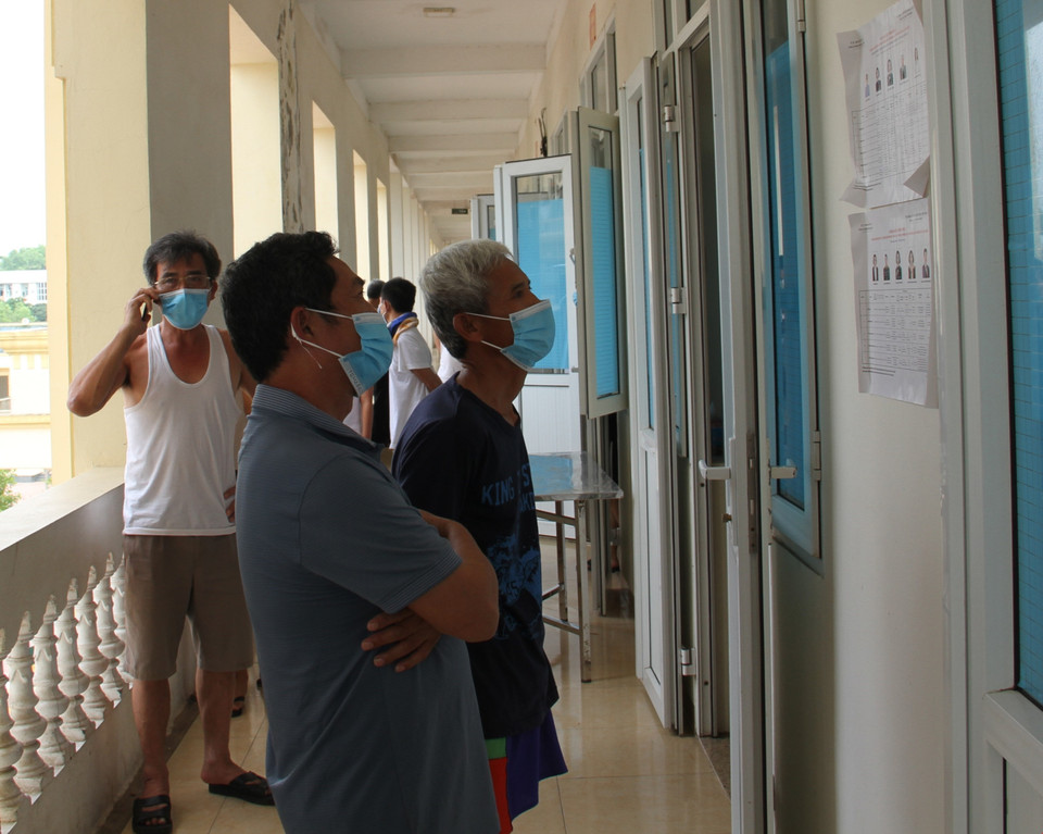 Các chiến sỹ và công dân xem tiểu sử ứng cử viên niêm yết tại khu cách ly phòng, chống dịch COVID-19 Trường Quân sự Bộ Tư lệnh Thủ đô Hà Nội. (Ảnh: TTXVN phát)