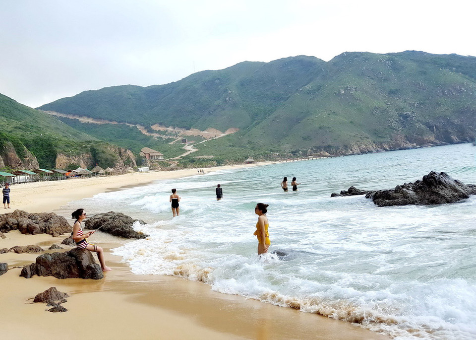 Khách du lịch đắm mình trong sóng nước trong veo ở bãi biển Kỳ Co. (Ảnh: Nguyên Linh/TTXVN)