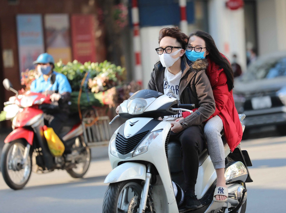 Hai bạn trẻ chủ quan, không thực hiện đội mũ bảo hiểm khi điều khiển và ngồi trên xe gắn máy (ảnh chụp lúc 16h, ngày 10/2/2021 trên phố Ngô Quyền, Hà Nội). (Ảnh: Thanh Tùng/TTXVN)