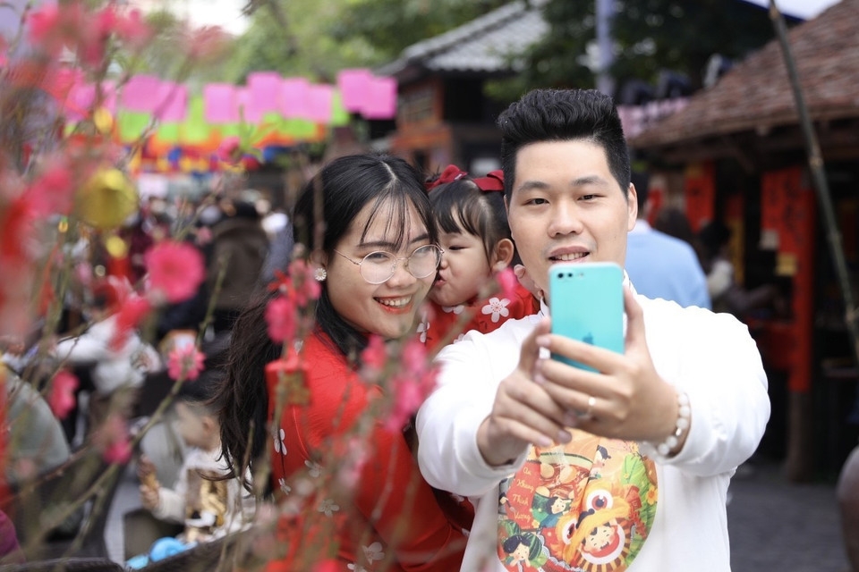  Nhiều gia đình đến chụp ảnh lưu lại những khoảnh khắc đầu Xuân mới. (Ảnh: Minh Quyết/TTXVN)