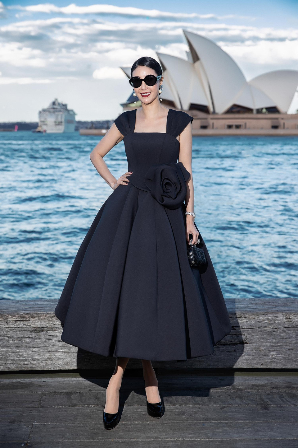 Hoa hậu Việt Nam 1992 Hà Kiều Anh điệu đà, trẻ trung trong dáng váy xoè rộng được tạo nên từ những đường cắt nối tinh tế. Thắt eo được nhấn nhá với hoạ tiết hoa 3D. Hoa hậu phối bộ cánh cùng áo clutch, mắt kính to bản, hoa tai ngọc trai và kiểu tóc búi cùng màu môi đỏ thẫm ấn tượng. (Ảnh: Diệu Linh/Vietnam+)