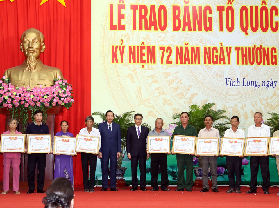 Phó Thủ tướng Vũ Đức Đam và Bộ trưởng Bộ Lao động Thương binh xã hội Đào Ngọc Dung trao Bằng Tổ quốc ghi công cho thân nhân các gia đình liệt sỹ tại Lễ trao Bằng Tổ quốc ghi công cho thân nhân, gia đình các liệt sỹ (22/7/2019). (Ảnh: Trọng Đức/TTXVN)