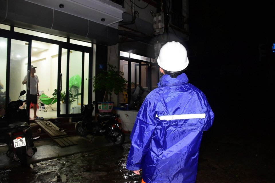 Công nhân Công ty Điện lực huyện Sóc Sơn kiểm tra an toàn để cấp điện trở lại cho các hộ dân thôn Lương Phúc ở ngoài đê Hữu Cầu, thuộc xã Việt Long, huyện Sóc Sơn từ 21h ngày 12/9. (Ảnh: TTXVN phát)