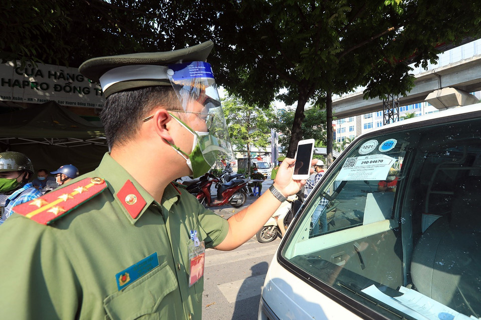 Công an kiểm tra mã QR đối với các xe vận tải chở hàng hóa ra, vào địa bàn phường Thanh Xuân Bắc.(Ảnh: Tuấn Anh/TTXVN)