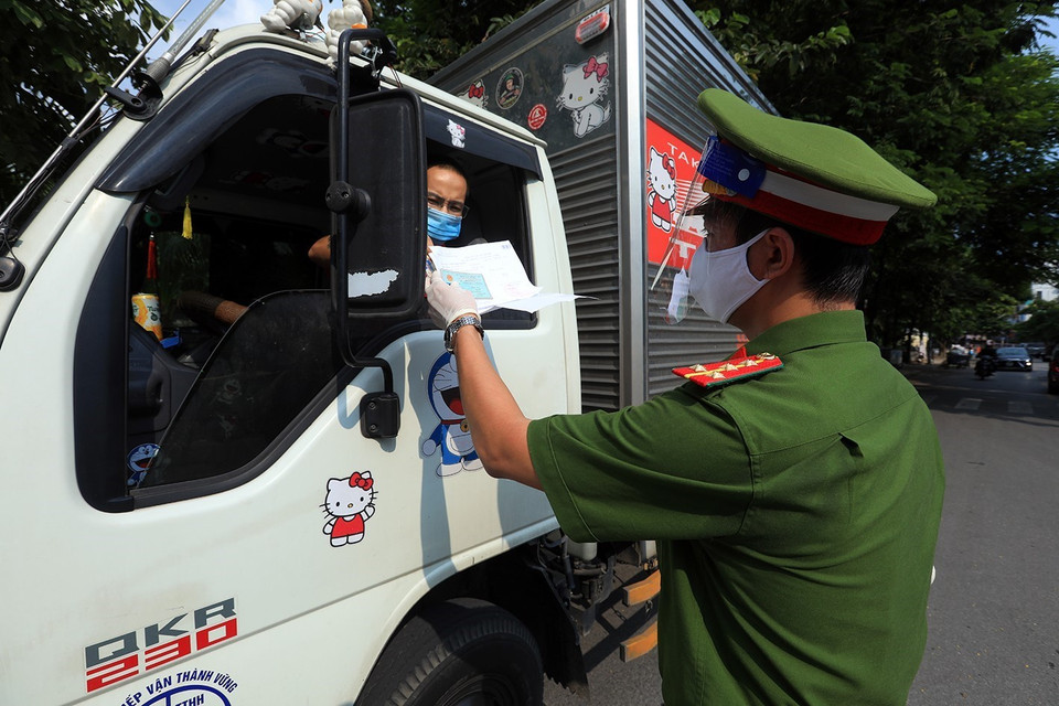Công an kiểm tra giấy đi đường và giấy phép vận chuyển hàng hóa thiết yếu của các phương tiện vận tải. (Ảnh: Tuấn Anh/TTXVN)