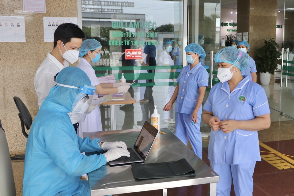 Các cử tri nhận phiếu bầu tại điểm bỏ phiếu Bệnh viện Bệnh Nhiệt đới Trung ương cơ sở 2. (Ảnh: TTXVN phát)