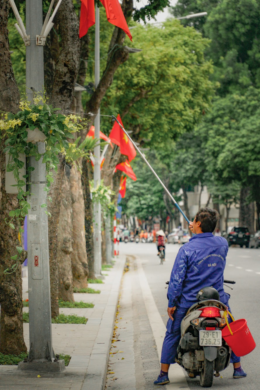 Nhân viên cây xanh đang tưới nước cho cây, hoa trong khuôn viên hồ Hoàn Kiếm. (Ảnh: Minh Hiếu/Vietnam+)