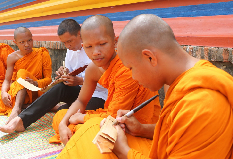 Người viết chữ trên lá buông, phải dùng một loại bút đặc biệt được làm bằng gỗ, vừa tay cầm, một đầu có mũi nhọn bằng kim loại gọi là Đek-cha để “khắc” chữ lên lá buông. Mỗi lá kinh sẽ viết được từ 4-5 dòng, mỗi dòng từ 15 đến 20 chữ. (Ảnh: Công Mạo/TTXVN)