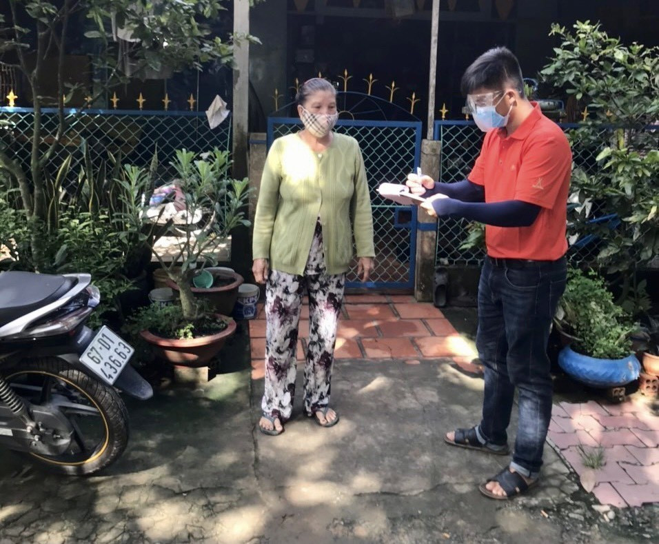 Nhân viên siêu thị đến từng nhà người dân ghi thông tin sản phẩm muốn mua vào giấy để tránh tập trung đông người. (Ảnh: Thanh Sang/TTXVN)