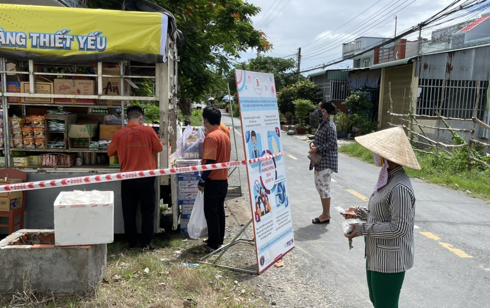 Người dân xếp hàng, giữ khoảng cách phòng, chống dịch bệnh chờ đến lượt mua hàng. (Ảnh: Thanh Sang/TTXVN)