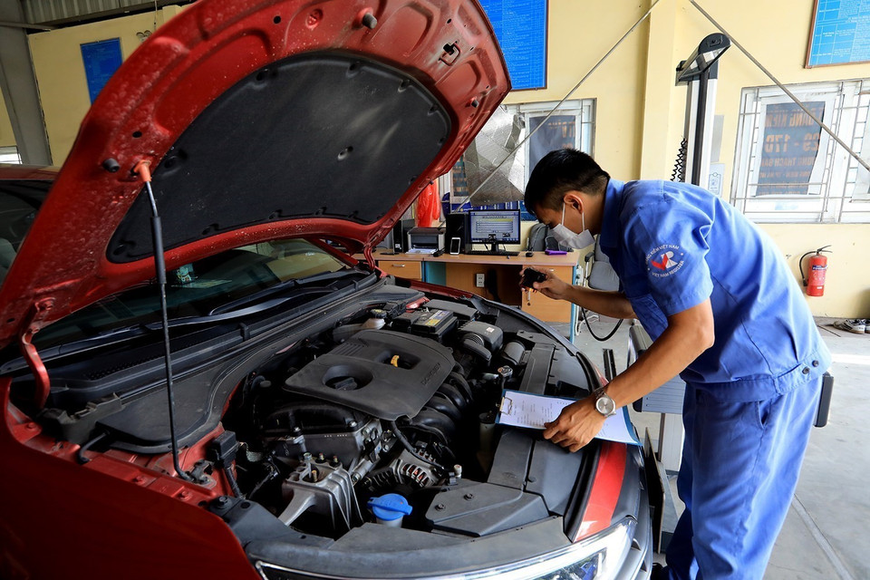 Đăng kiểm viên Trung tâm đăng kiểm 29-17D kiểm tra thông số kỹ thuật phương tiện đến đăng kiểm. (Ảnh: Tuấn Anh/TTXVN)