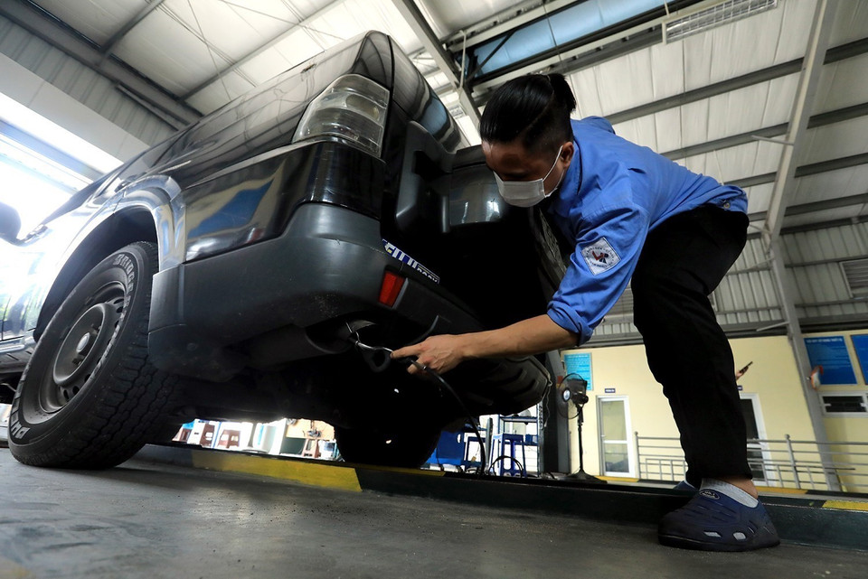 Đăng kiểm viên Trung tâm đăng kiểm 29-17D đo lượng khí thải của phương tiện đến đăng kiểm. (Ảnh: Tuấn Anh/TTXVN)