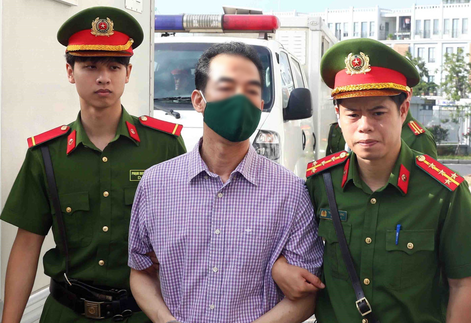 Lực lượng chức năng dẫn giải bị cáo Tô Anh Dũng, cựu Thứ trưởng Bộ Ngoại giao, tới phiên tòa xét xử. (Ảnh: Phạm Kiên/TTXVN)