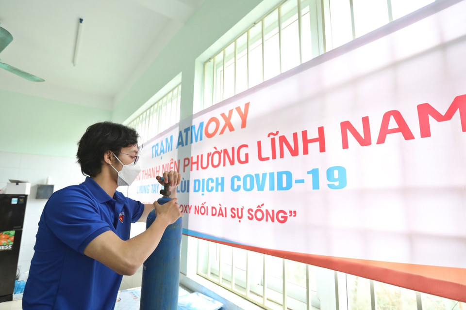 Thành viên Tổ hỗ trợ theo dõi người nhiễm COVID-19 tại nhà phường Lĩnh Nam kiểm tra bình oxy trước khi mang đến hỗ trợ F0 cách ly y tế, điều trị tại nhà. (Ảnh: Minh Quyết/TTXVN)