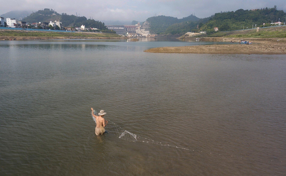 Người dân lội nước giăng lưới bắt cá ngay giữa dòng sông Đà. (Ảnh: Trọng Đạt/TTXVN)