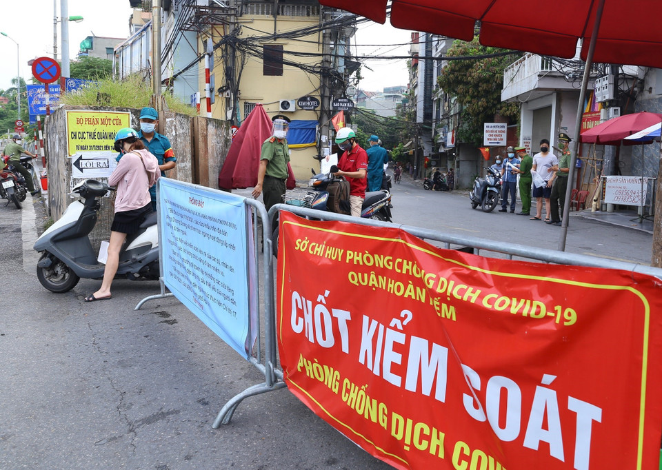 Công an kiểm tra giấy tờ đi đường của người dân phường Chương Dương khu vực được phép ra ngoài khi cần thiết (ảnh chụp sáng 17/8 tại cửa khẩu Cầu Đất). (Ảnh: Hoàng Hiếu/TTXVN)