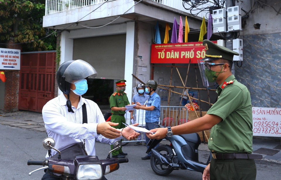 Người dân phường Chương Dương khu vực được phép ra ngoài khi cần thiết trình giấy tờ với lực lượng chức năng. (Ảnh: Hoàng Hiếu/TTXVN)