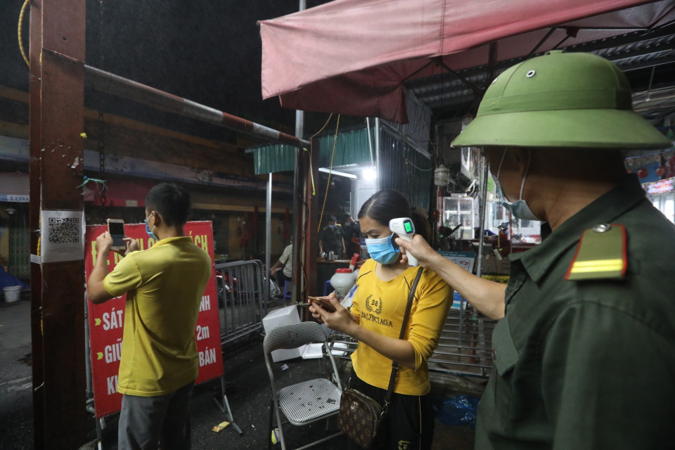 Tiểu thương phải kiểm tra thân nhiệt, khai báo y tế trước khi vào chợ. (Ảnh: Minh Quyết/TTXVN)