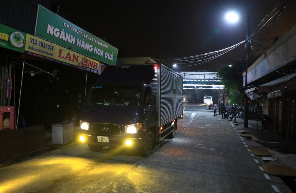 Những chiếc xe tải đầu tiên hoàn tất thủ tục khai báo y tế được phép vào chợ Long Biên hoạt động. (Ảnh: Thành Đạt/TTXVN)