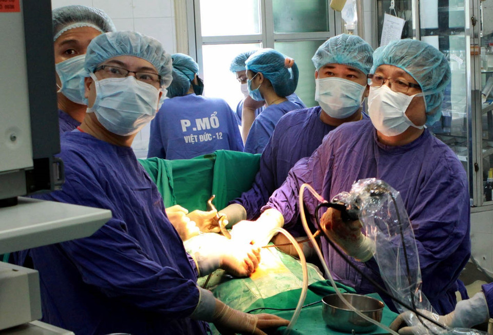 Phó giáo sư, tiến sỹ, anh hùng lao động, thầy thuốc nhân dân Nguyễn Tiến Quyết, Giám đốc Bệnh viện Hữu nghị Việt Đức (Bộ Y tế), là người đi đầu thực hiện thành công ca ghép gan từ người sống, người chết não - một trong những thành tựu y học xuất sắc của ngành Y tế Việt Nam. Gần 40 năm gắn bó với nghề, ông đã nỗ lực phấn đấu không mệt mỏi, nghiên cứu, tìm tòi, say mê với công việc đầy nhọc nhằn và vinh quang. Trong ảnh: GS.TS Nguyễn Tiến Quyết (bên phải) cùng kíp mổ thực hiện lấy sỏi đường mật gan bằng kỹ thuật nội soi tán sỏi để bảo tồn gan cho người bệnh. (Ảnh: Dương Ngọc/TTXVN)