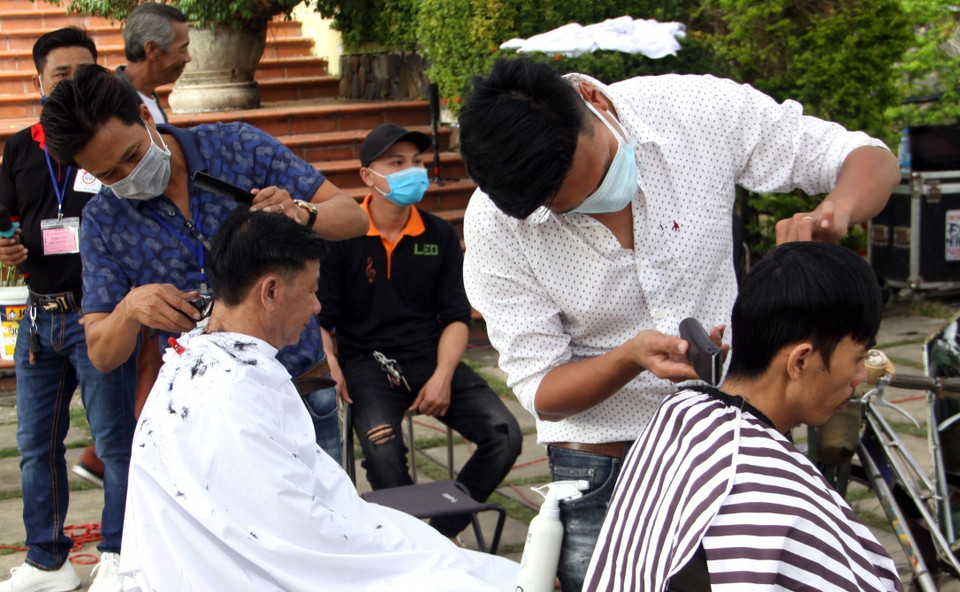 Người dân cắt tóc miễn phí tại Phiên chợ không đồng tổ chức tại Trung tâm bảo tồn di tích Hội An (Quảng Nam). (Ảnh: Trịnh Bang Nhiệm/TTXVN)
