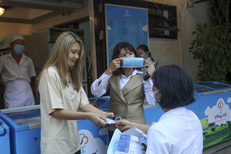 Nhân viên y tế phường phát khẩu trang cho những người chưa tuân thủ quy định về phòng, chống dịch bệnh. (Ảnh: Tuấn Đức/TTXVN)